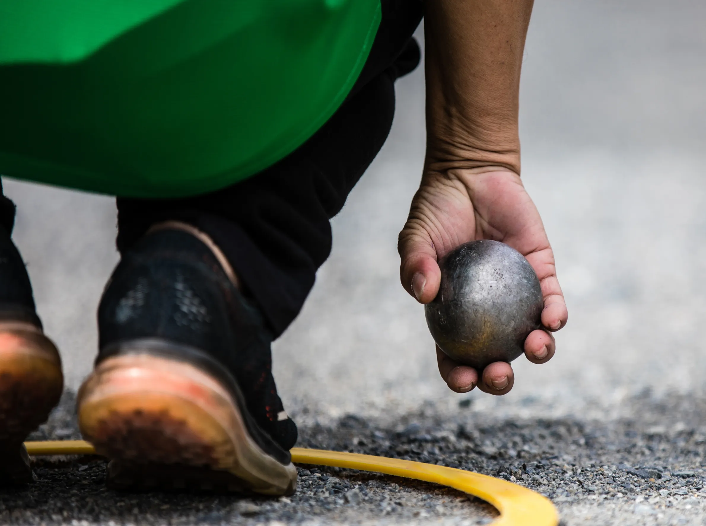 Person greppar en metallkula vid utomhusspel – symbol för återställd motorisk funktion trots OFF-episoder vid Parkinsons sjukdom