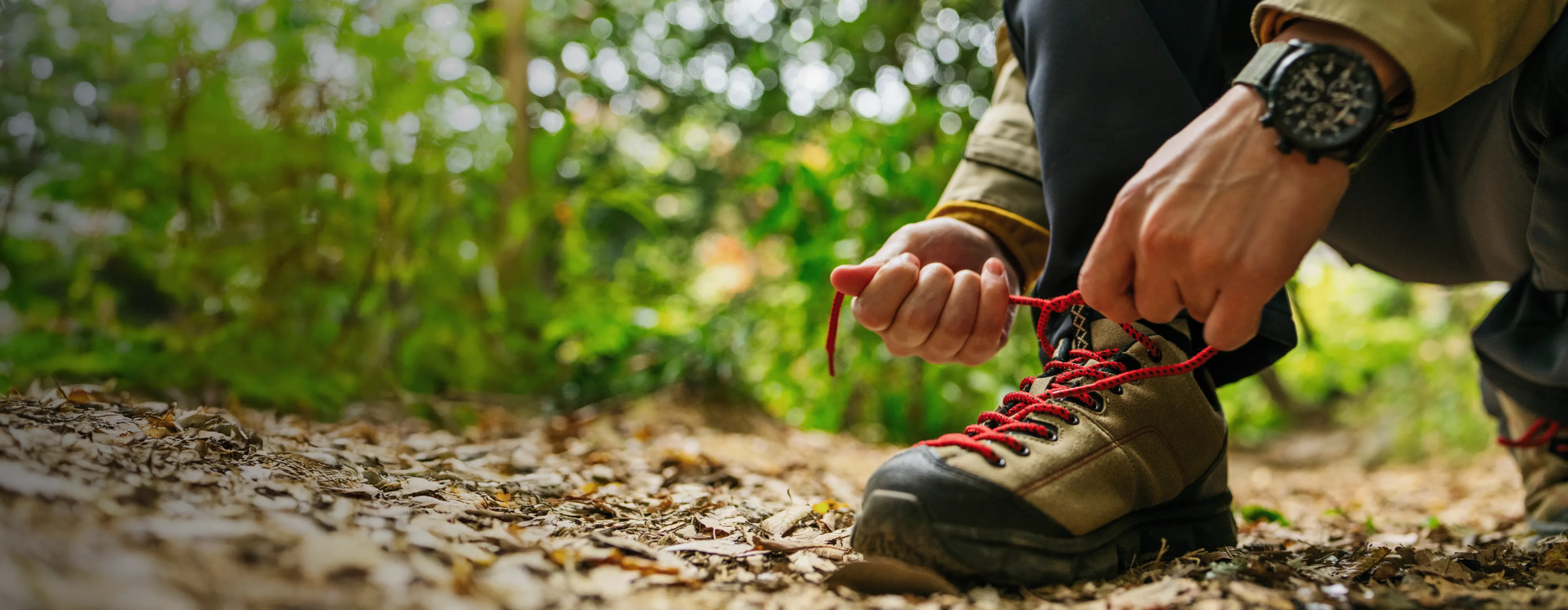 Person knyter vandringssko i skogen – symbol för aktivitet trots Parkinsons sjukdom och OFF-episoder